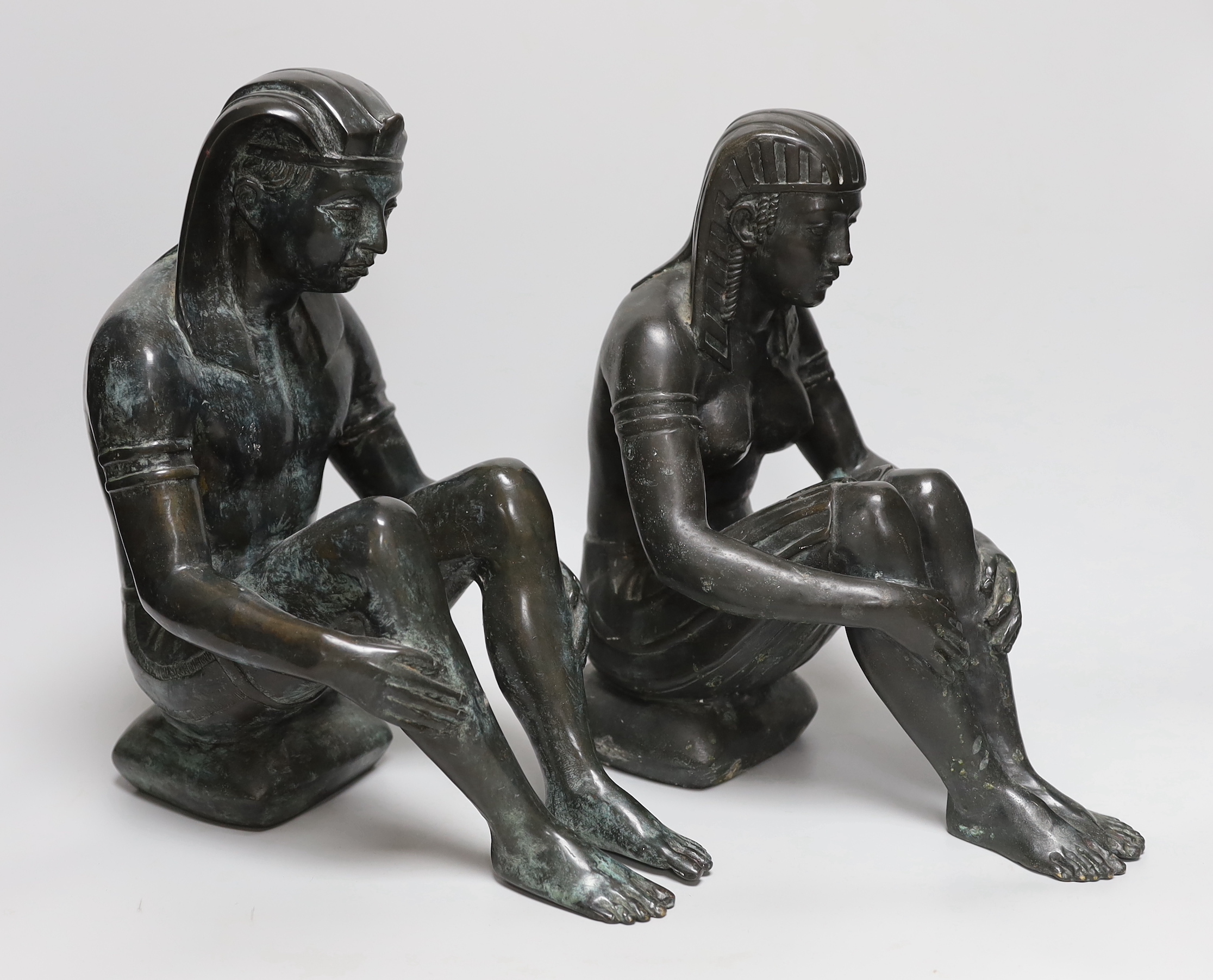 A pair of cast bronze seated Egyptian figures wearing headdresses, the largest 30cm high